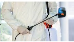 Uomo in piedi con tuta, guanti e strumenti per la disinfestazione